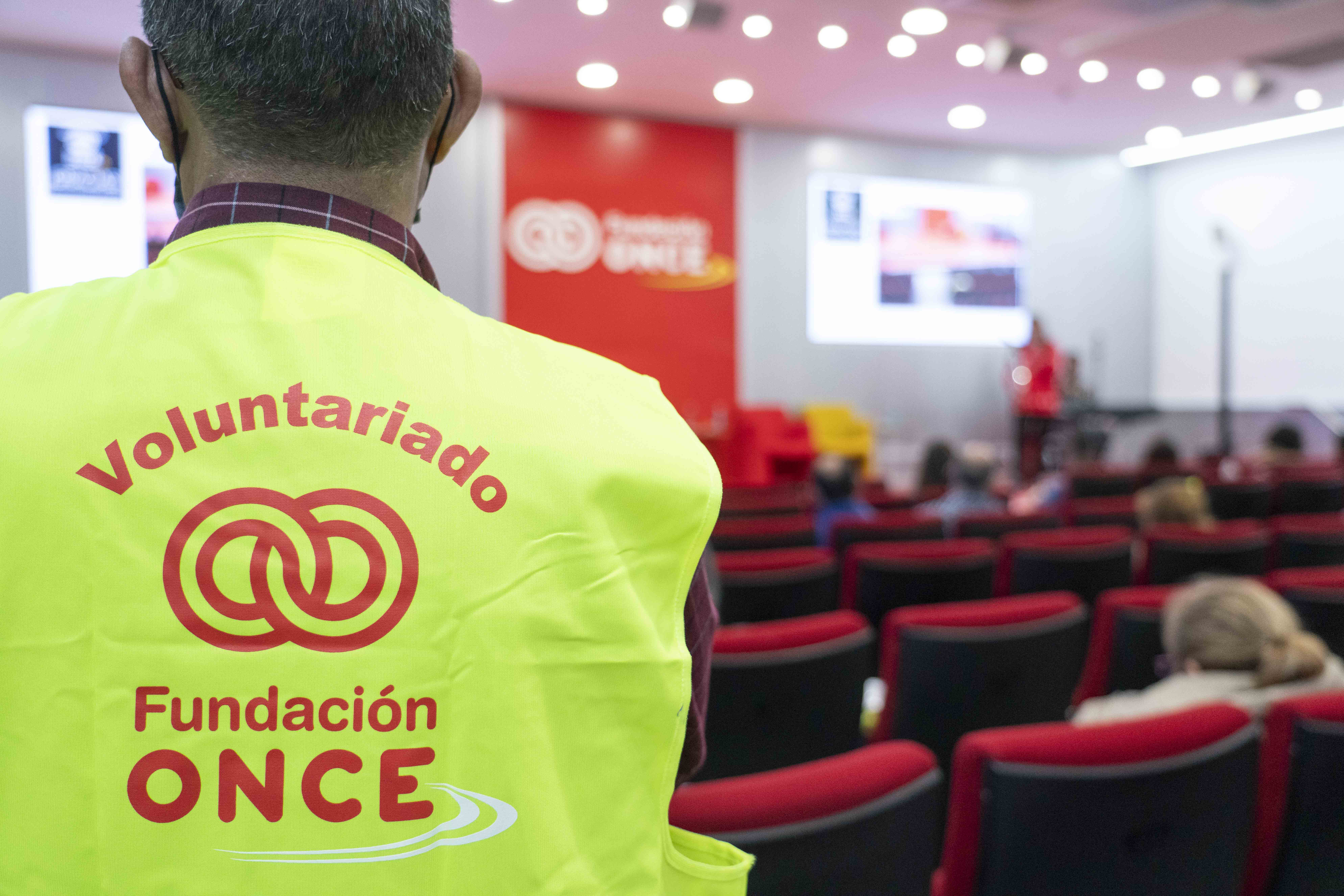Voluntario de Fundación ONCE identificado con su chaleco en un acto